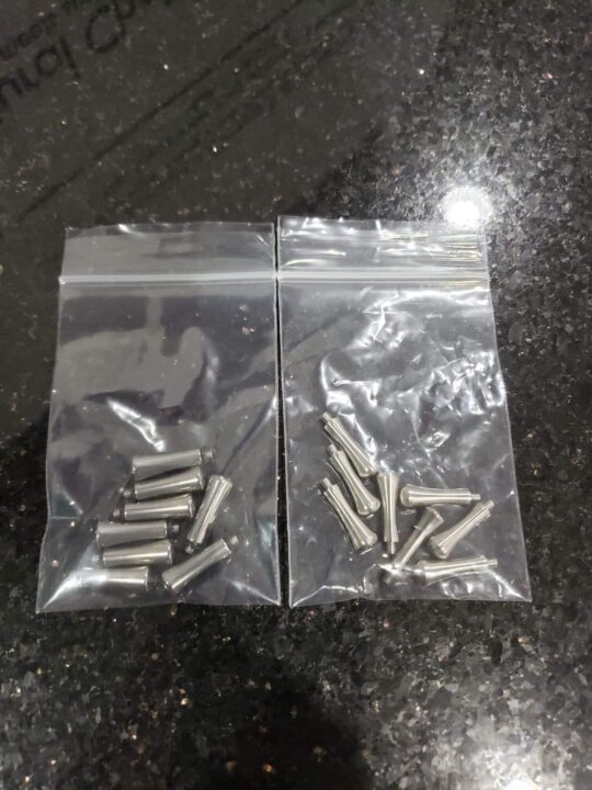 Two clear plastic bags containing Tangs / Finger Rests are placed on a black speckled surface.